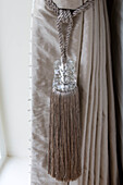 Glass tassel with silk curtains in living room of London home   England   UK