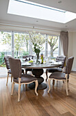 Buttoned dining chairs at circular table below skylight in London home   England   UK