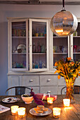 Beleuchtete Teelichter auf Holztisch mit gläserner Kommode in der Küche von King's Lynn Norfolk England UK