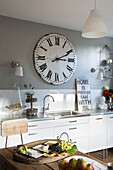 Große Vintage-Uhr über der Spüle in einer Berkshire-Küche mit Käseplatte, England, UK