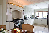 Lit candle on table in white fitted kitchen of Chobham home   Surrey   England   UK