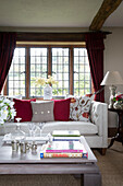 Couchtisch und Sofa mit Bleiglasfenster im Wohnzimmer eines Bauernhauses in Sussex England UK