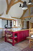 Open plan kitchen with beamed ceiling and red island unit in Sussex farmhouse   England   UK