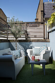 Sessel und Sofa mit Tisch auf Kunstrasen im eingezäunten Hinterhof eines Londoner Stadthauses England UK