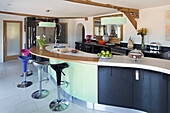 Colourful bar stools at curved island unit in Sandhurst kitchen  Kent  England  UK