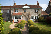 Ziegelpfad mit Formschnitthecke vor einem freistehenden Haus in East Dean, West Sussex, Vereinigtes Königreich