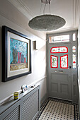 Artwork above radiator cover in tiled entrance hallway of contemporary London home, England, UK