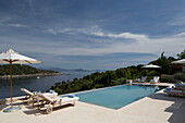 Sonnenliegen und Sonnenschirme am Pool mit Meerwasser und Blick auf die Ägäis auf der griechischen Insel Ithaka