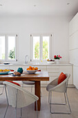 Korbstühle an einem Holztisch mit offenen Fenstern in einer Villa auf der griechischen Insel Ithaka
