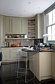 Metal barstools at breakfast bar in modern kitchen of London townhouse UK