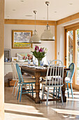 Assorted chairs with seat cushions at wooden dining table in Surrey home England UK