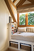 Striped fabrics on daybed below window in Surrey home England UK