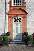 Schotterauffahrt und Eingangstür eines Landhauses aus Stein und Ziegeln in Sussex, England, UK