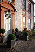 Backstein und Mauerwerk mit Sonnenlicht, das sich in den Fenstern eines freistehenden Landhauses in Sussex spiegelt England UK