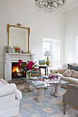 Gilt framed mirror above lit fire in living room of Sussex country house England UK