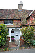 Offenes Tor zur weiß gestrichenen Eingangstür eines gefliesten Landhauses in Surrey, England, UK