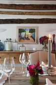 Weingläser und brennende Kerze auf hölzernem Esstisch in Surrey home England UK
