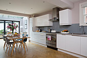 Spacious fitted kitchen with lilies on table in Victorian family home in South West London UK