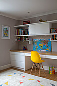 Gelber Stuhl am Schreibtisch mit Landkarte und Regalen in einem Jungenzimmer in South West London UK