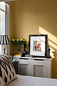 Framed print of horse on radiator cover at bedside in London townhouse apartment UK