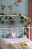Daisy-chain and bunting on headboard of girls bed in 19th century Somerset cottage England UK