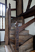 Old wooden staircase and banisters with fabric at leaded glass window in timber framed farmhouse Kent UK