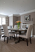 Dining table and chairs with cut tulips and coir matting in Victorian terraced house London England UK