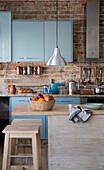 Edelstahl-Hängeleuchte über einem Obstkorb in einer Küche in Sussex (England) mit Ziegelsteinen