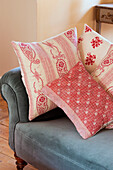 Assorted red cushions on blue velvet sofa in Sussex home England UK