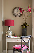 Rote Lampe und Orchidee mit Uhr über dem Schreibtisch in einem Haus in Sussex England UK