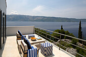 Armchairs with footstools on balcony terrace of Ithaca villa with view to sea Greece