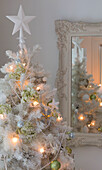 Star on top of artificial Christmas tree decorated with fairylights and baubles in South London home England UK