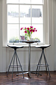 Pink Peonies (Paeonia) and bar stools in at window in London townhouse England UK