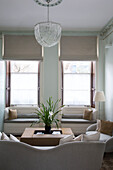 Glass pendant shade in neutral classic living room with window seats in London townhouse England UK