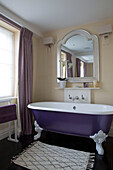 Purple freestanding bath with classic mirror in London townhouse England UK