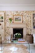 decanter and glasses on table with bookcase and feature wall in Gloucestershire home England UK