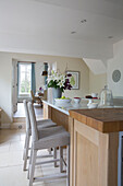 Wicker bar stools and cut lilies in kitchen of Worcestershire home England UK