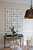 Cut lilies and botanical prints with antique pendant shade in Worcestershire dining room England UK