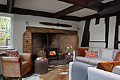 Brown leather armchair at lit exposed brick fireside in Worcestershire home England UK