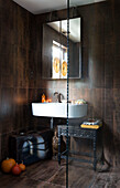 Mirror above washbasin with carved side table in London home England UK