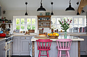 Bemalte rosa Barhocker in offener Küche in Sussex, England, UK