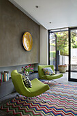 Pair of lime green armchairs with zig-zag rug in modern London townhouse England UK