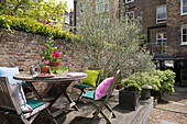 Tisch und Stühle im Freien auf einer Terrasse im Garten eines Londoner Stadthauses (England)