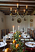 Candlelit dining table at Christmas in timber-framed Hampshire farmhouse England UK