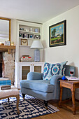 Gerahmtes Kunstwerk über hellblauem Sessel mit hölzernem Beistelltisch in Gloucestershire Cottage UK