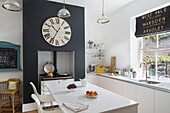 Weiße Barhocker an Kücheninsel mit großer Uhr in Brighouse West Yorkshire UK