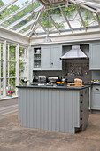 Light grey fitted kitchen with stainless steel extractor in conservatory extension of London townhouse UK