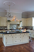 Marble-topped island unit with parquet floor in cream fitted kitchen of Kent country house England UK