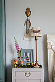 Cream lamp with brass heart and single stem flower at bedside in Cheshire home UK
