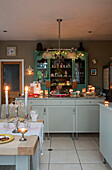 Green glass fronted cabinet with lit candles in Cheshire kitchen UK